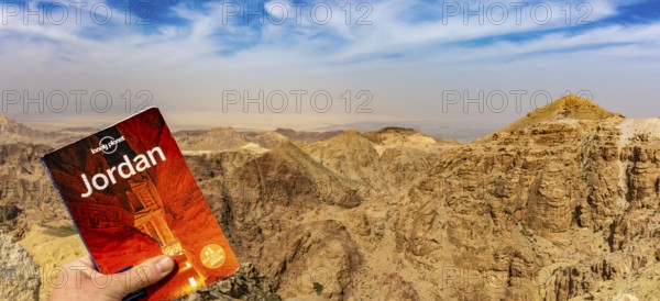 Lonely Planet travel guide against dramatic Jordan mountains and sky to promote travel and tourism to Jordan