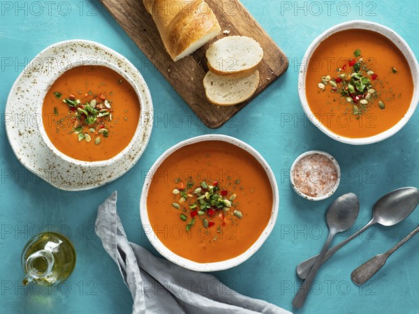 Gaspacho soup on blue tabletop. Three bowls of traditional spanish cold soup puree gaspacho or gazpacho on bright blue background. Top view or flat lay