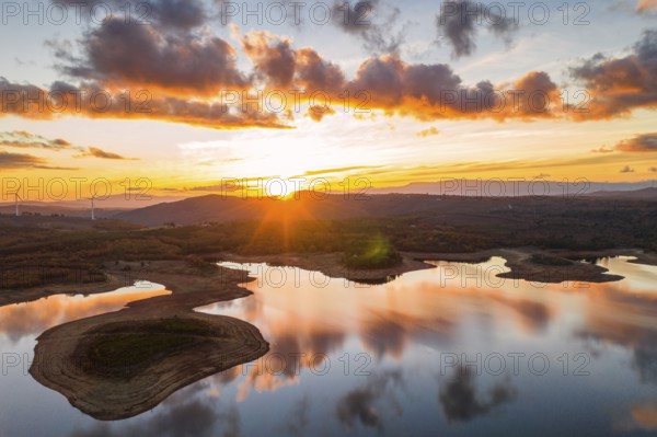 Drone aerial view of a lake reservoir of a dam with perfect reflection on the water of the sunset in Sabugal, Portugal, Europe