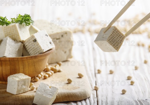 Soy Bean curd tofu in wooden bowl on white wooden kitchen table. Non-dairy alternative substitute for cheese. Place for text