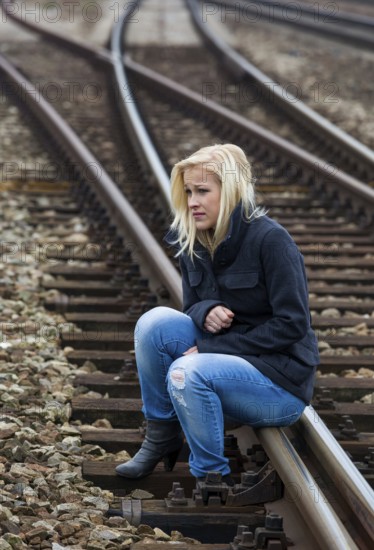 A young woman is sad, anxious and depressed. Sits on a railway track and is lonely