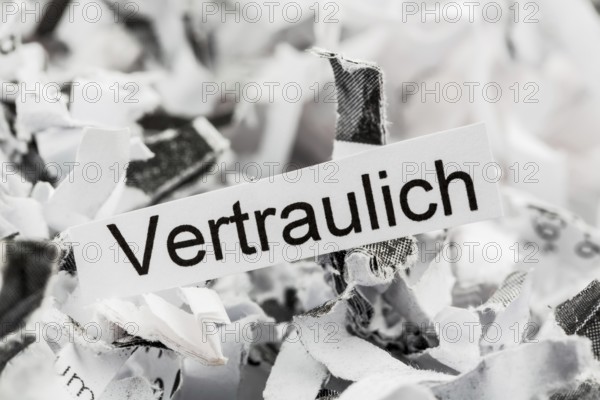 Paper shreds with the keyword Confidential, symbolic photo for data destruction and confidentiality