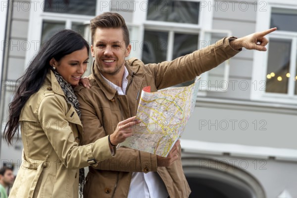 Young couple with city map and travel guide while visiting a city on holiday Austria