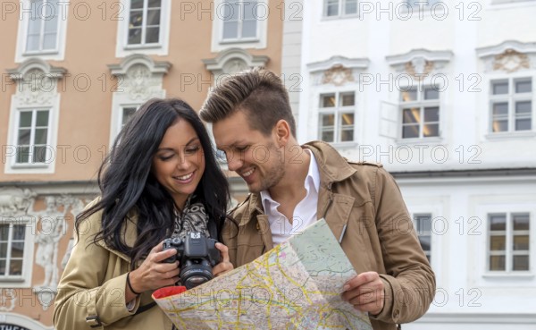 Young couple with city map and travel guide while visiting a city on holiday Austria