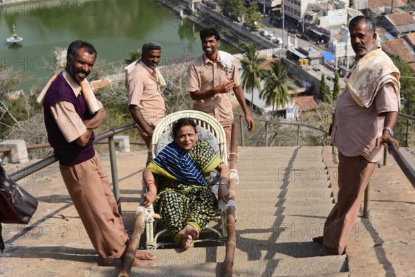 Transport to the Gomateshwara statue, Jaina-Asket, Jain temple on Vindyagiri Hill, Shravanabelagola, Karnataka, South India, India, Person in a chair, carried on a steep staircase, surrounded by smiling men with a city view, Mysore, Karnataka, South India, India, Asia