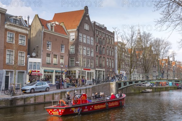 Amsterdam, Netherlands, March 31, 2016: Cruise boat at Amsterdam canals in Holland, bridge, people and street view
