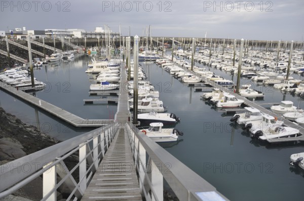 Saint-Quay Portrieux, A marina filled with white boats and docks under an overcast sky, viewed from a descending walkway