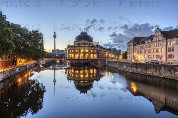 The Bode Museum and the television tower are reflected in the Spree in Berlin in front of sunrise