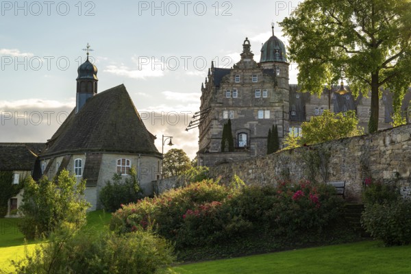 Historic Hämelschenburg Castle with castle church, well-tended garden and old walls in the evening light, Weserbergland, Lower Saxony, Germany, Europe