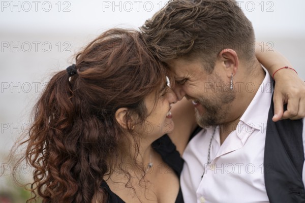 Couple looking into each other's eyes smiling about to kiss on a beach