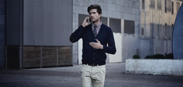 Young businessman talking smartphone phone walking on the street