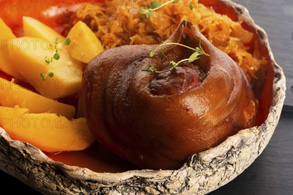 Appetizing baked pork knuckle with potatoes and cabbage on plate