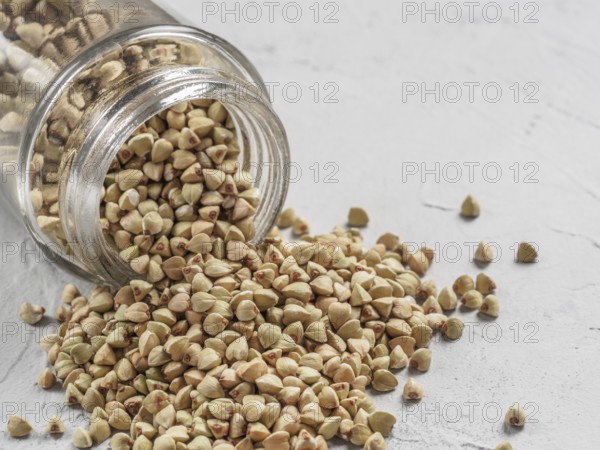 Raw green buckwheat in bank on gray background