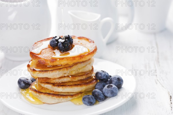 Pancakes with blueberry and honey on a white plate