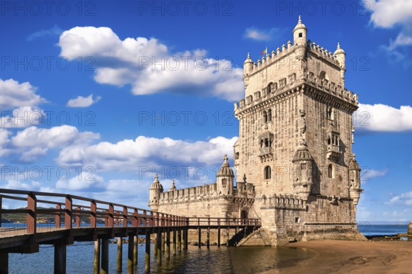 Belem tower and wooden bridge to it, Lisbon, Portugal at blue summer day sky with clouds. Medieval fort on Tagus river in late Gothic or Manueline style, UNESCO world heritage site, Age of Discoveries, tourist attraction, Portuguese seafaring history