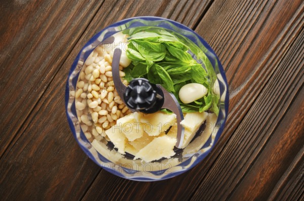 Ingredients for italian national traditional genovese pesto sauce in food processor bowl. Flat lay view