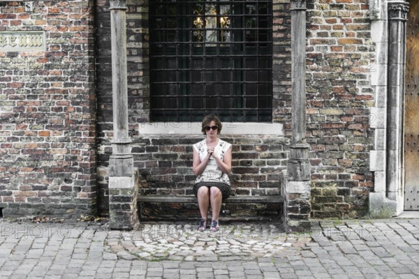 Playful portrait of a praying young tourist girl in Bruges, Belgium, July 2017, Europe