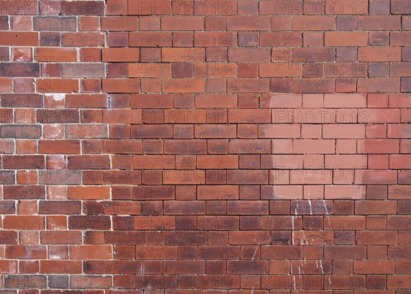 An old repaired patched exterior wall made of red bricks
