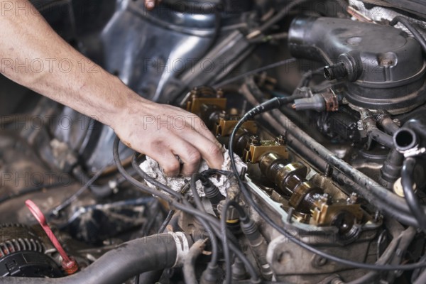 Auto mechanic working on car engine at repair service. Close up view