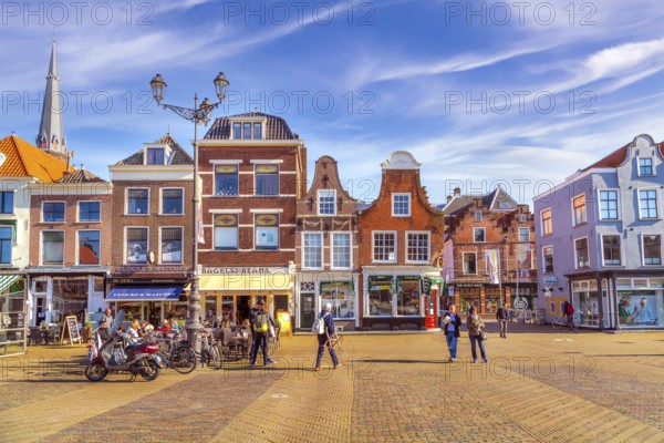 Delft, Netherlands, April 8, 2016: Colorful street view with traditional dutch houses on the square, bicycles, people in downtown of popular Holland destination