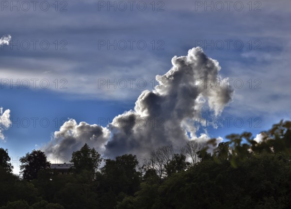 Threatening thundercloud grows behind a house into the blue sky, dramatic cloud formation, Upper Bavaria, Bavaria, Germany, Europe