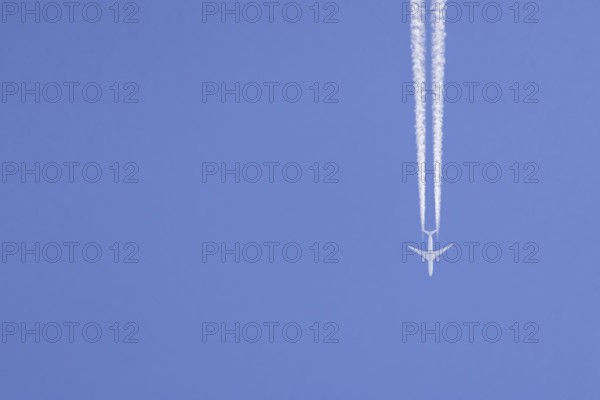 Airbus aircraft of Qatar airways flying across a blue sky with a vapour trail or contrail behind, England, United Kingdom, Europe