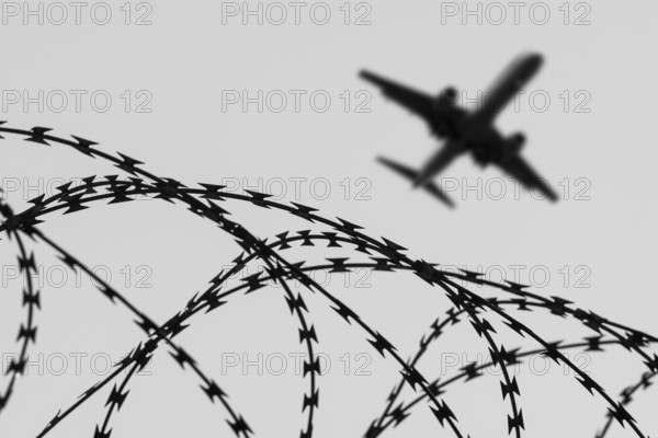 Symbolic image, deportation flights of illegal and delinquent migrants, passenger aircraft, airport, security fence, barbed wire, black and white image, Germany, Europe