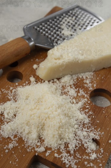 Freshly sliced and grated cheese, parmesan cheese, Gran gusto. Grana padano. on a wooden chopping board, rustic style, no people