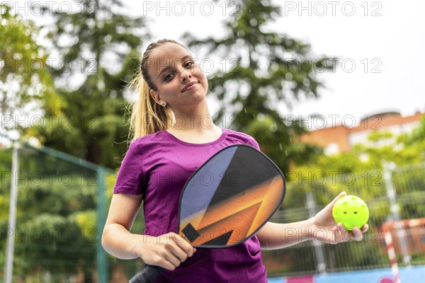 Portrait of a young pickelball woman player with racket and ball in an outdoor pitch