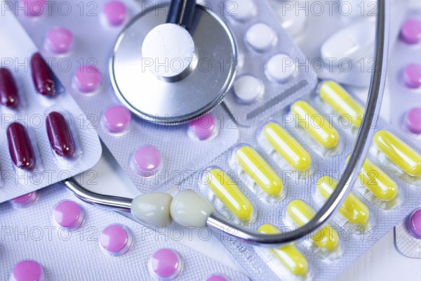 Blister packs with colorful pills alongside a stethoscope