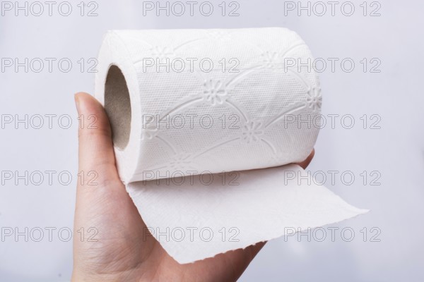 A female hand takes a roll of white toilet paper in hand