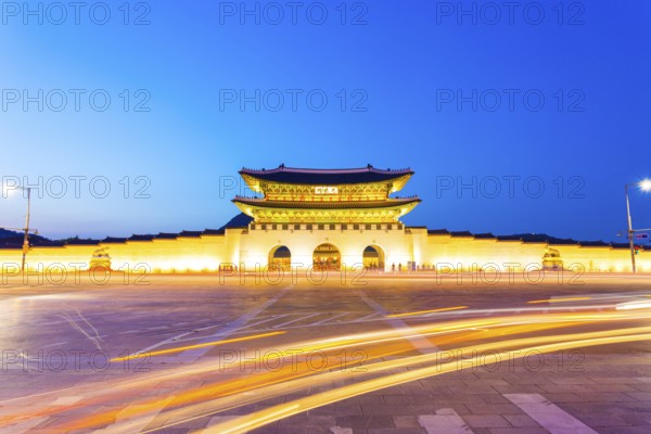 Long exposure car lights curving in front of Gwanghwamun main entrance gate to Gyeongbokgung Palace in historic part of downtown Seoul, South Korea on a clear, dusk night