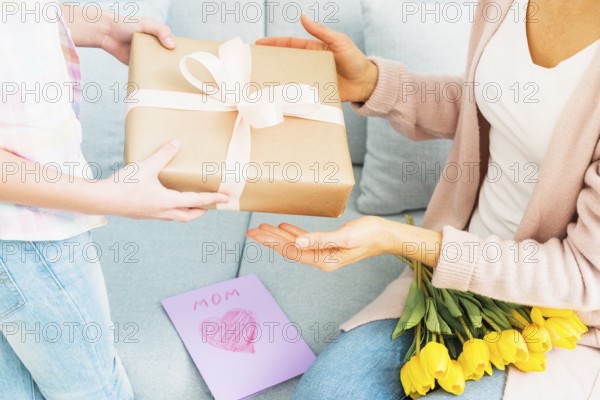 Daughter presenting gift box mom mother s day celebration