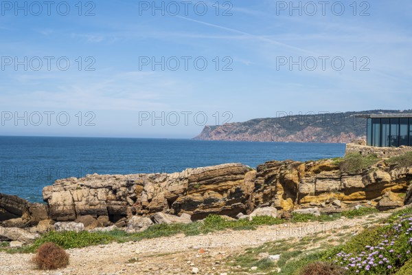 View of a modern coastline with rocks and blue sea under a blue sky, coast in Portugal Praia de Arriba
