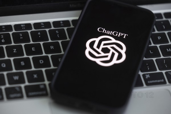 OpenAI software ChatGPT application on a mobile phone above a computer keyboard