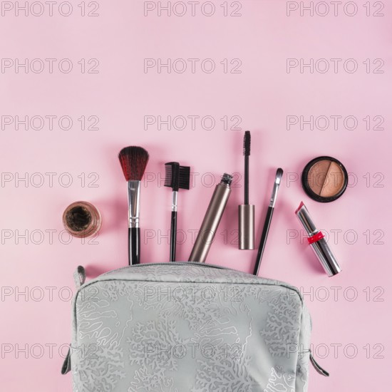 Makeup products spilling out bag pink background