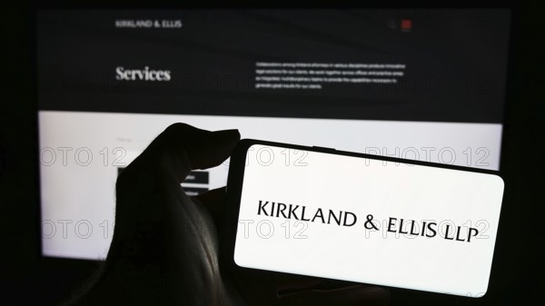 Stuttgart, Germany, 12-15-2023: Person holding mobile phone with logo of American law firm Kirkland and Ellis LLP in front of business web page. Focus on phone display, Europe