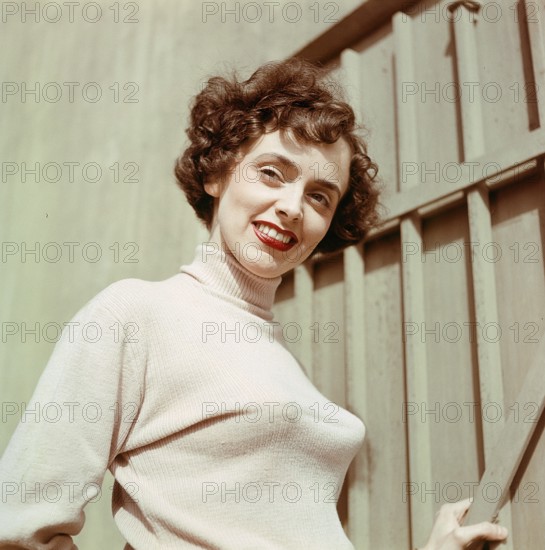 1950s jumper fashion. A swedish young woman wearing a typical 50s sweater. Under it she is wearing a bullet bra. The popular type of bra had bra cups in the shape of a paraboloid and was made popular due to sweater girl pin-ups. Sweden 1950s. CV5-10