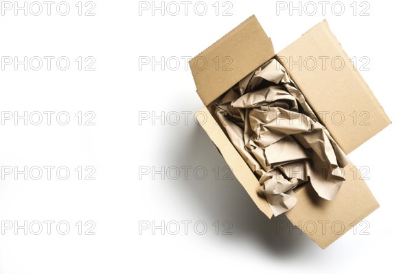 Large packaging for small goods on white, without plastic but natural cardboard box and a lot of paper, waste of resources and trees with many online orders and deliveries, copy space, selected focus