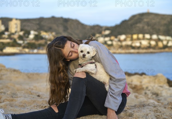 Girl playing with maltichon puppy dog in the beach