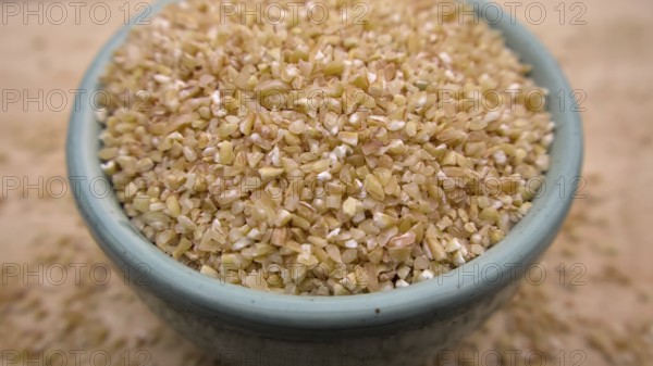 Broken Crushed Wheat (Dalia) in a Blue Bowl Isolated on Wooden Background, Close up