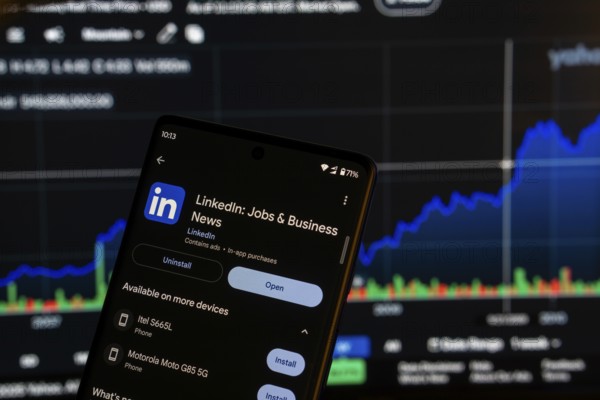 Dhaka, Bangladesh 08 March 2025: Linkedin jobs and business app installation screen on a smartphone and the financial market chart in the background