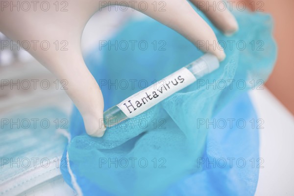 Gloved hand holding a Hantavirus labeled test tube over a blue cloth