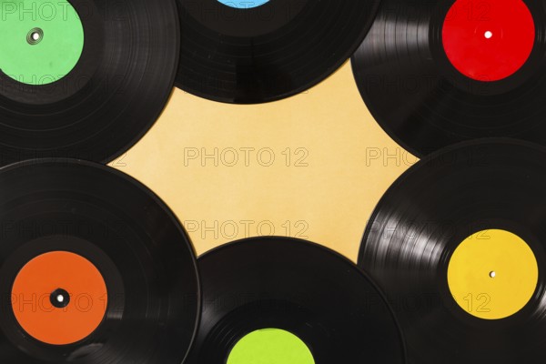 Overhead view colorful black vinyl record beige background