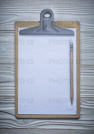 Vertical version clipboard with blanc paper copyspace and pencil on vintage white painted wood