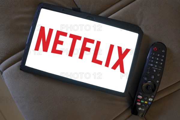 April 20, 2024, Brazil. In this photo illustration, the logo of the global provider of films and series via stream Netflix seen displayed on a tablet next a Tv remote control