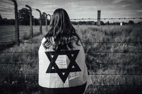Jewish girl with Israeli flag by the fence of the concentration camp
