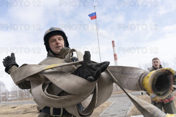 PETROPAVLOVSK CITY, KAMCHATKA PENINSULA, RUSSIA, APR 19, 2019: Firefighter-rescuer Emercom of Russia collects long fire hose on hands. Firefighters and rescuers (fire-fighting) sport competitions