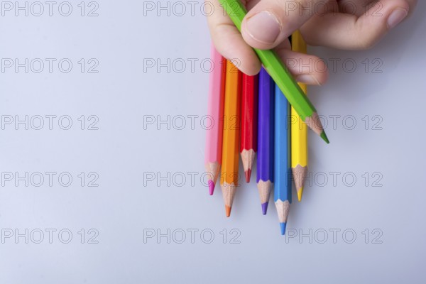 Hand holding color Pencils placed on a white background
