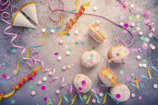 Traditional Berliner for carnival and party. German Krapfen or donuts with streamers and confetti. Colorful carnival or birthday image